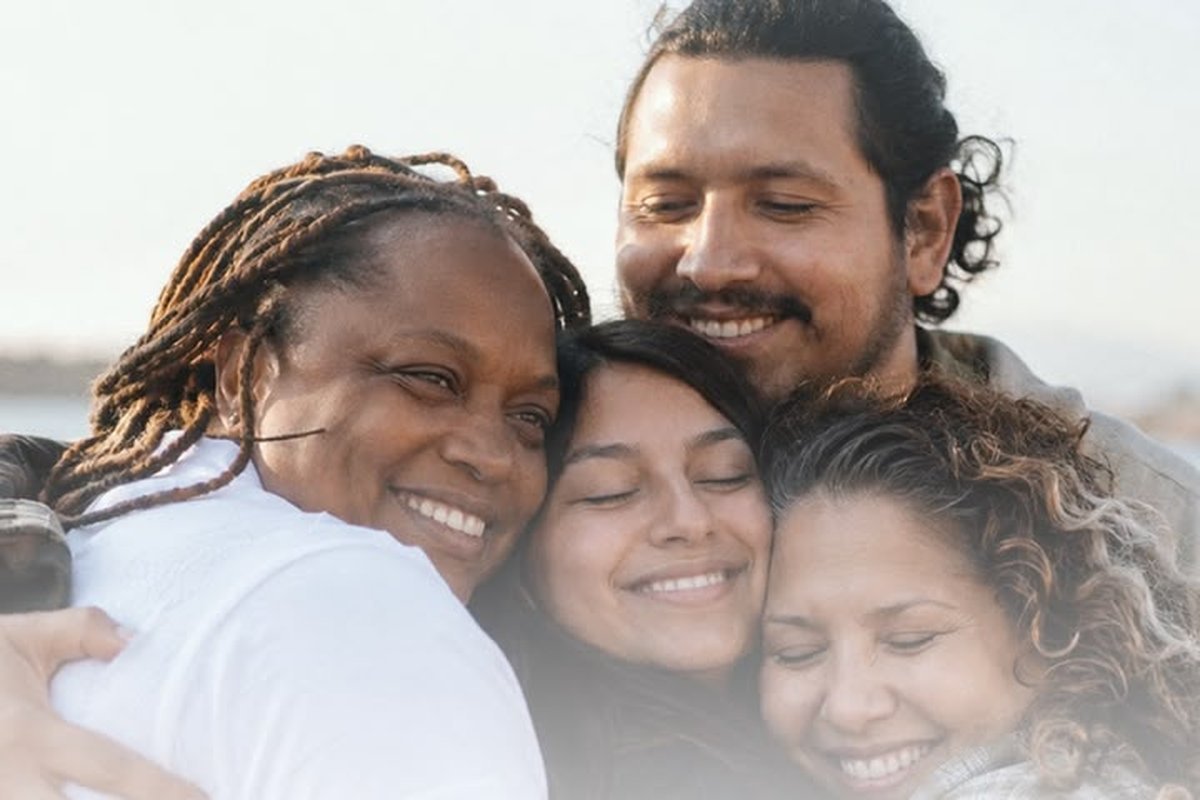Cuatro personas se abrazan sonriendo